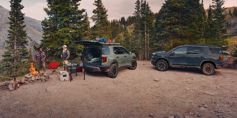 2027 Honda Passport TrailSport Elite in Ash Green Metallic profile parked at a mountain campsite (Mid-Size SUV).