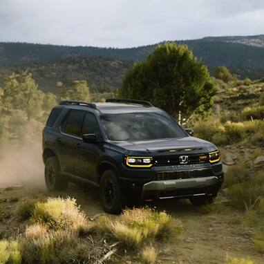 2027 Honda Passport TrailSport Elite in Smoke Blue Pearl front driving on a dusty off-road trail (Mid-Size SUV).